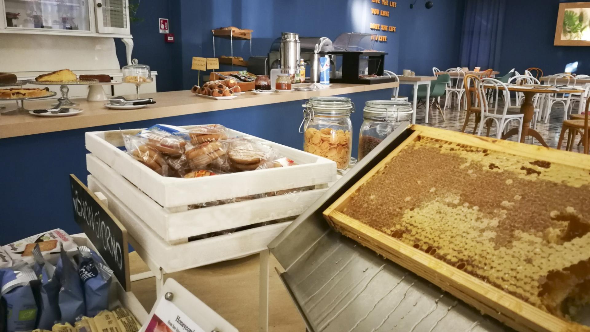 Buffet per colazione con miele, dolci confezionati e cereali in un ambiente accogliente.