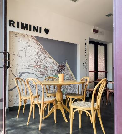 Caffetteria accogliente con mappa di Rimini e arredi in legno chiaro.