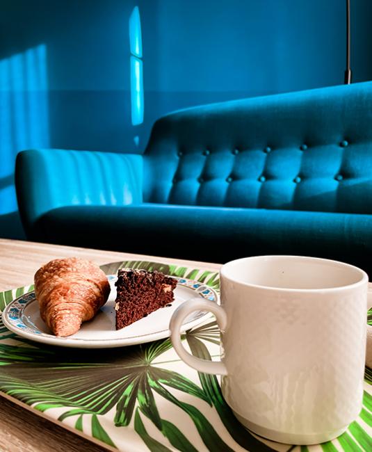 Colazione con croissant e torta al cioccolato su un vassoio tropicale.