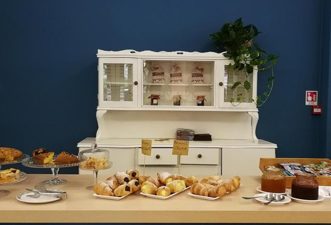 Bambino raccoglie miele da un favo in un buffet con persone sullo sfondo.