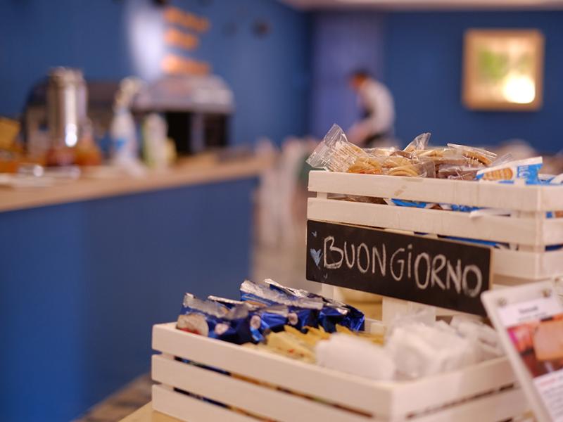 Cestino con snack e scritta 'Buongiorno' in un ambiente accogliente.