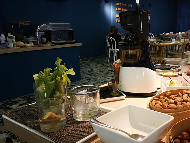 Colazione a buffet con frutta, frullatore e mandorle in un ambiente accogliente.