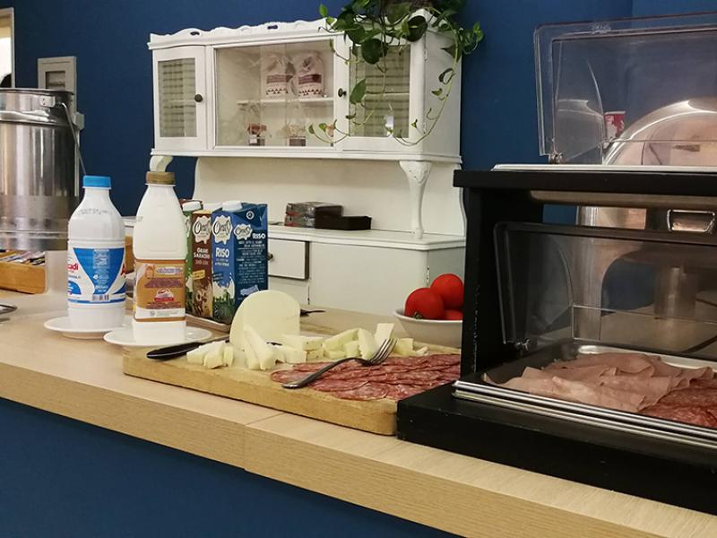 Buffet con formaggi, salumi, bevande vegetali e latticini su un tavolo di legno.