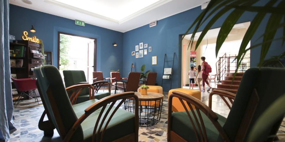 Sala d'attesa accogliente con poltrone, tavolini e decorazioni su pareti blu.